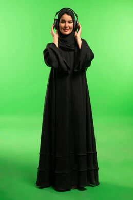 امرأة سعودية بسماعات رأس أمام خلفية كروما خضراء