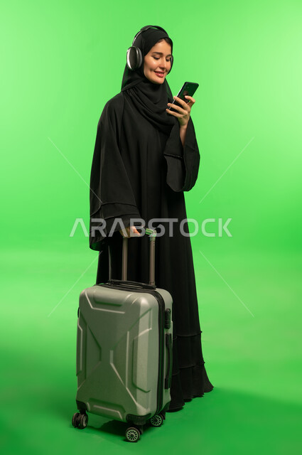 امرأة سعودية مع حقيبة سفر وهاتف على كروما خضراء