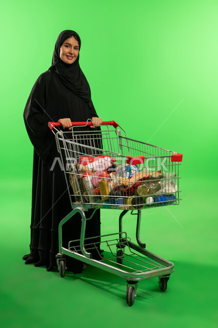 امرأة سعودية مع عربة تسوق على خلفية خضراء