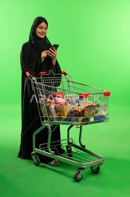 امرأة سعودية مع عربة تسوق على خلفية خضراء