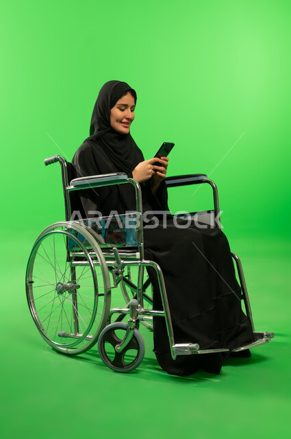 امرأة سعودية على كرسي متحرك مع هاتف خلفية خضراء