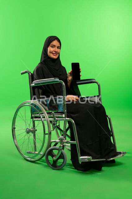 امرأة سعودية على كرسي متحرك مع هاتف خلفية خضراء