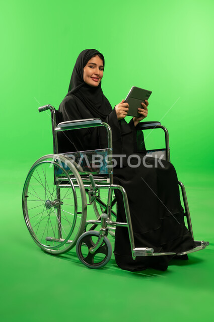 امرأة سعودية على كرسي متحرك مع تابلت بخلفية خضراء