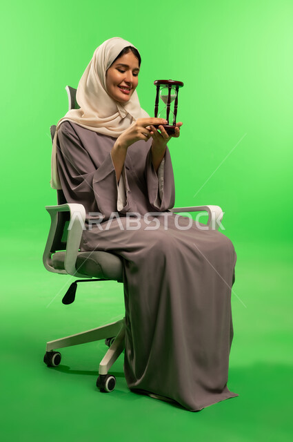 Saudi Woman Holding Hourglass on Green Screen Background
