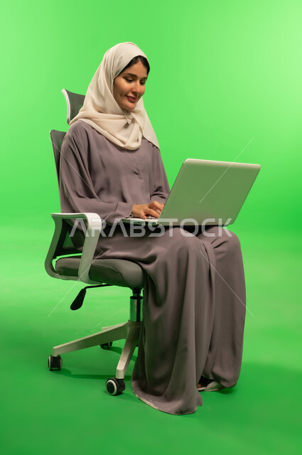 Saudi Woman Using Laptop on Green Screen Backdrop