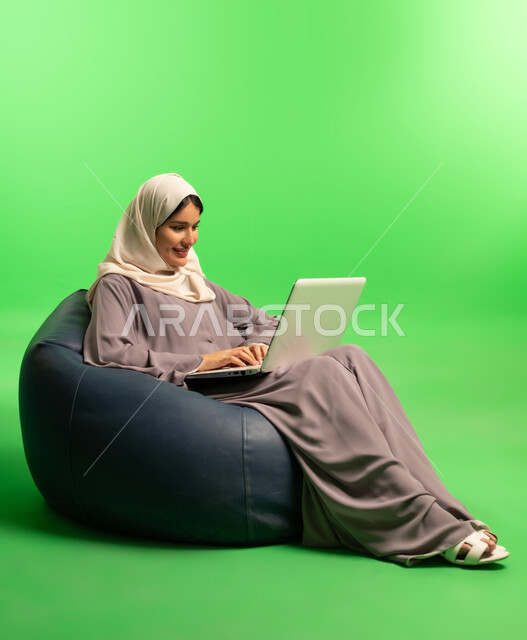 Saudi Woman Using Laptop on Beanbag with Green Screen