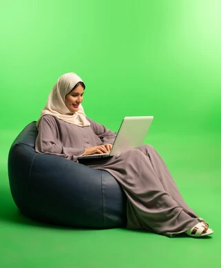 Saudi Woman Using Laptop on Beanbag with Green Screen