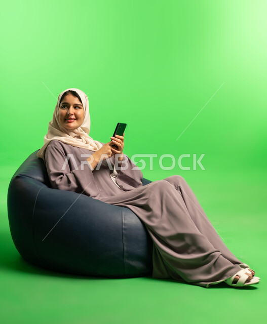امرأة سعودية مع هاتف ذكي أمام خلفية خضراء