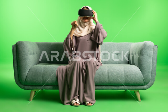 امرأة سعودية ترتدي نظارة واقع افتراضي بخلفية خضراء