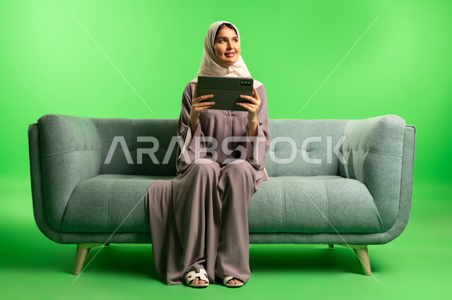 Saudi Woman with Tablet on Green Screen Sofa