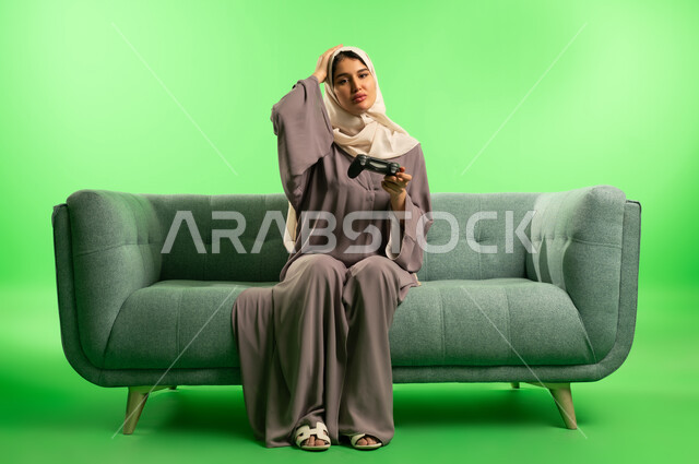 امرأة سعودية مع جهاز تحكم ألعاب بخلفية خضراء