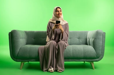 امرأة سعودية مع هاتف ذكي أمام خلفية خضراء امرأة سعودية مع هاتف ذكي أمام خلفية خضراء