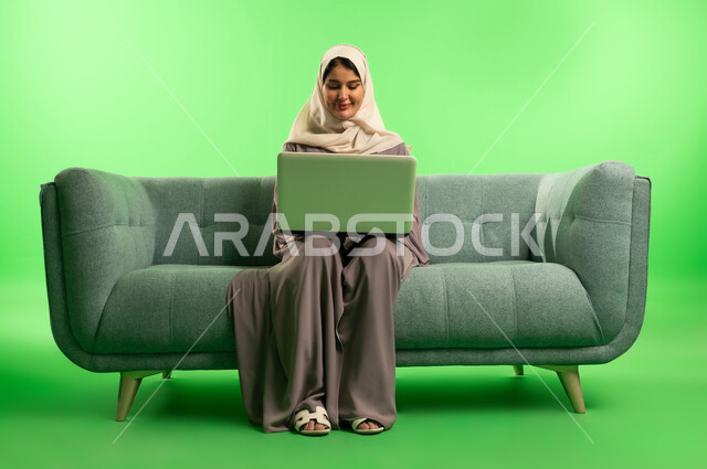 Saudi Woman with Laptop on Sofa Green Screen
