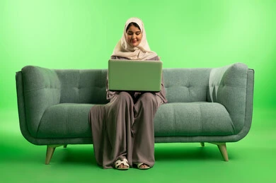 Saudi Woman with Laptop on Sofa Green Screen