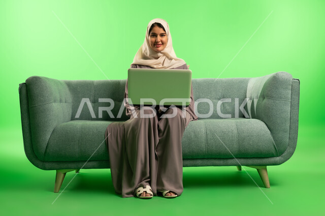 Saudi Woman Using Laptop on Green Screen Sofa