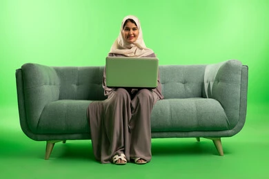 Saudi Woman Using Laptop on Green Screen Sofa