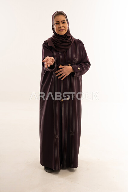 امرأة عربية مسنة بالعباءة تمد يدها في الاستوديو