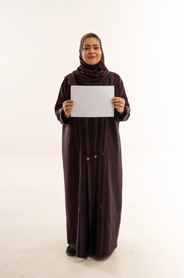 امرأة عربية بعباءة تحمل لوحة بيضاء فارغة