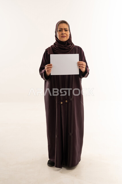 امرأة سعودية مسنة تمسك لوحة بيضاء فارغة في استوديو
