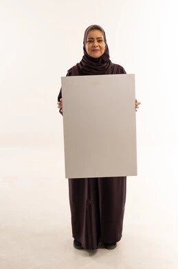 امرأة سعودية تحمل لوحة بيضاء فارغة كبيرة