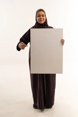 امرأة سعودية تمسك لوحة بيضاء فارغة في استوديو