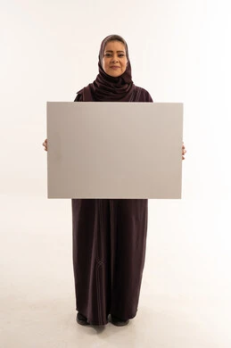 امرأة عربية تحمل لوحة بيضاء فارغة في استوديو