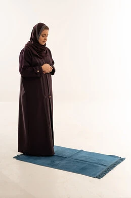 امرأة سعودية تصلي بعباءة على سجادة صلاة