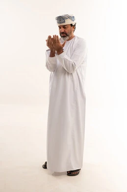 رجل عماني بالزي التقليدي يدعو أمام خلفية بيضاء