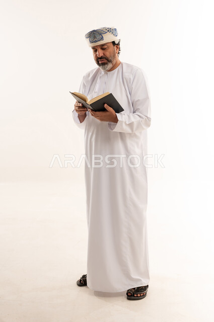 رجل عُماني بالزي التقليدي يقرأ كتاباً