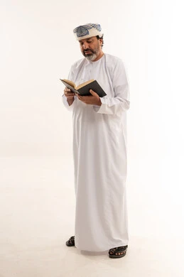 رجل عُماني بالزي التقليدي يقرأ كتاباً