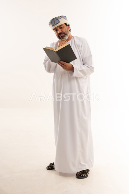 Omani Man in Traditional Dress Reading Book