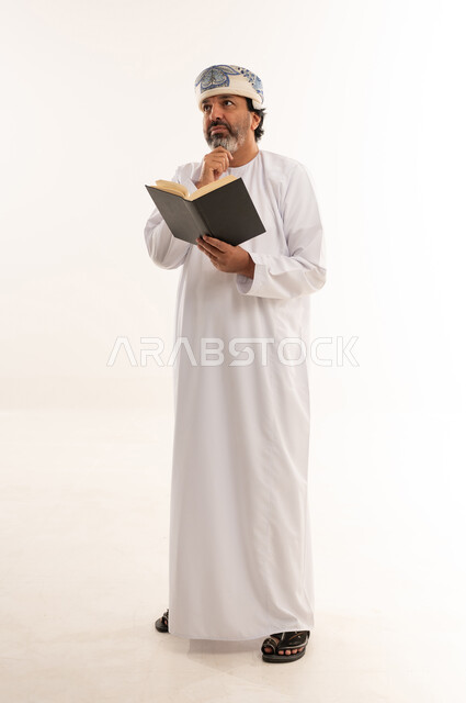 Omani Man in Traditional Dress Thinking with Book