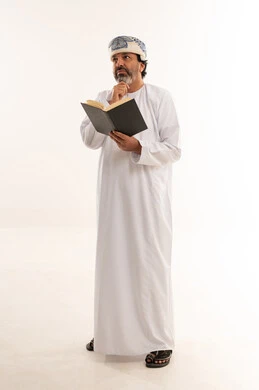 Omani Man in Traditional Dress Thinking with Book