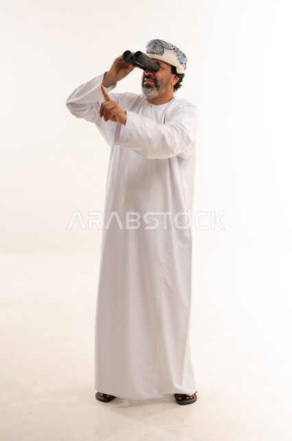 رجل عماني بالزي التقليدي يستخدم المنظار في الاستوديو