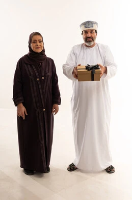 زوجان عمانيان مع صندوق هدايا بخلفية بيضاء