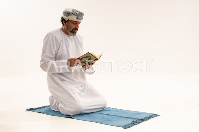 Omani Man Reading Quran on Prayer Mat Studio Shot