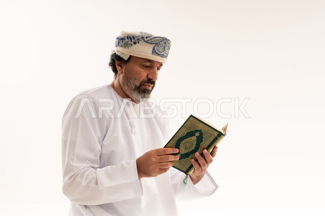 إسلاميات وعبادة ، حفظ وقراءة القران الكريم ، رجل عربي خليجي عماني يرتدي الدشداشة والعمامة يحمل بيده المصحف الشريف ، الإكثار من ذكر الله تعالى .
