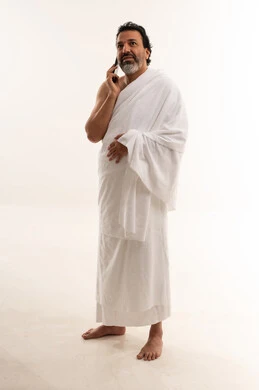 رجل عربي بملابس الإحرام يتحدث في الهاتف المحمول