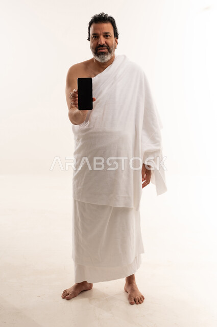 Arab Man in Ihram Holding Smartphone Studio Shot