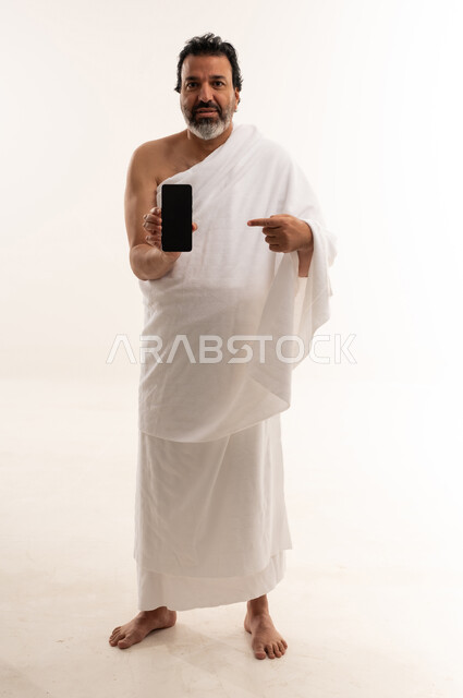 رجل بملابس الإحرام يشير إلى شاشة جوال
