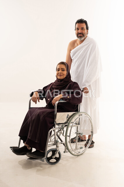 رجل سعودي وامرأة مسنة على كرسي متحرك بملابس الإحرام