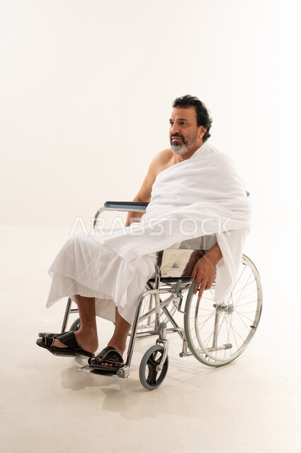 Arab Pilgrim in Ihram Sitting in Wheelchair Studio Shot