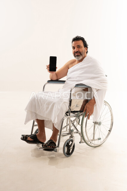 Saudi Pilgrim in Wheelchair Holding Smartphone