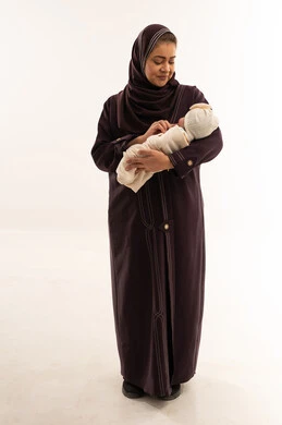 أم سعودية بالعباءة تحمل طفلها حديث الولادة