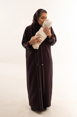 أم سعودية بالعباءة تقبل طفلها حديث الولادة