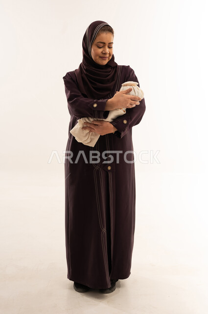 أم سعودية بعباءة بنفسجية تحمل طفلاً حديث الولادة