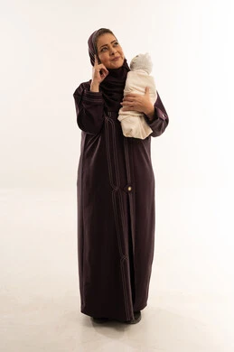 أم سعودية بالعباية تحمل رضيعاً في وضعية تفكير