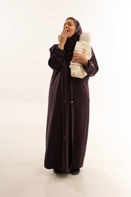 Tired Saudi Mother Yawning While Holding Newborn Baby