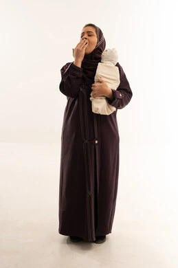 Tired Saudi Mother Yawning While Holding Newborn