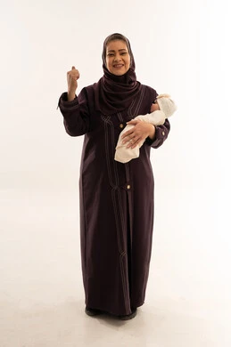 امرأة سعودية بالعباءة تحمل طفل رضيع